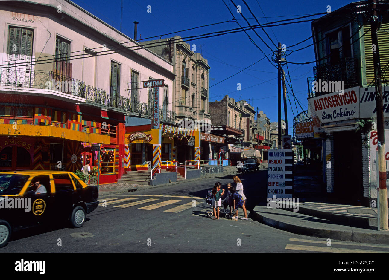buildings roads and woman with childrens on a pedestrian crossing in calle Necochea of Boca Buenos Aires Argentina Stock Photo