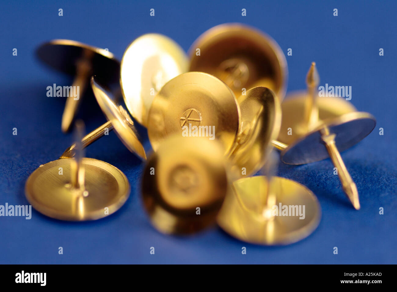 Gold thumb tacks drawing pins on blue background Stock Photo