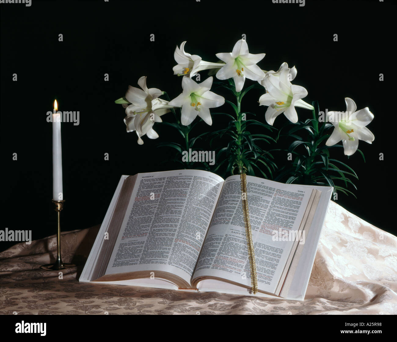 Easter still life with Bible and candle and display of Easter lilies ...