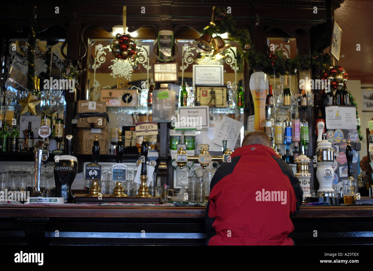 A lone drinker sits at the bar of a public house in Birmingham with a pint of beer. Stock Photo