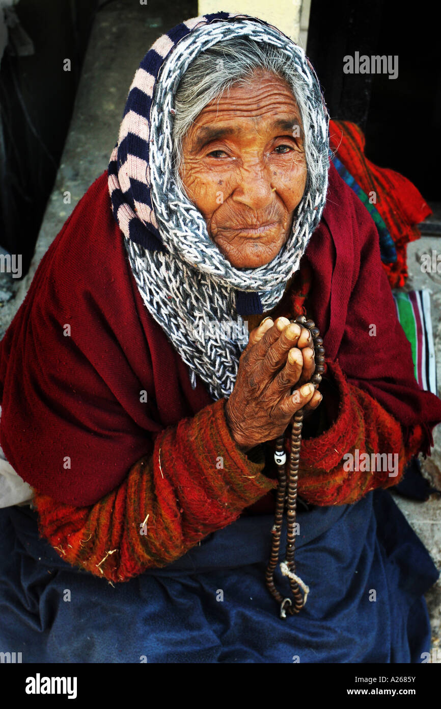 Tibetan Buddhist lady praying on the street in  Dharamsala Northern India  with beads Stock Photo