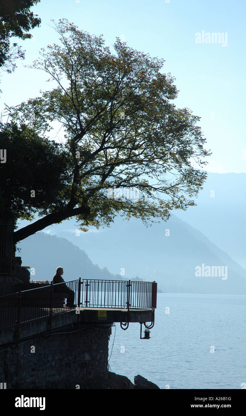 one old man sitting in shade of tree overlooking lake como Stock Photo