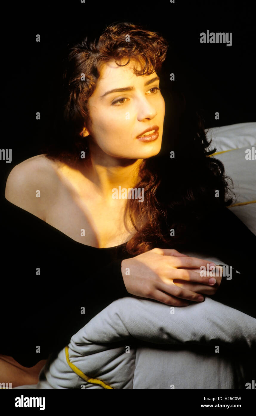Young woman sitting on a bed Stock Photo - Alamy