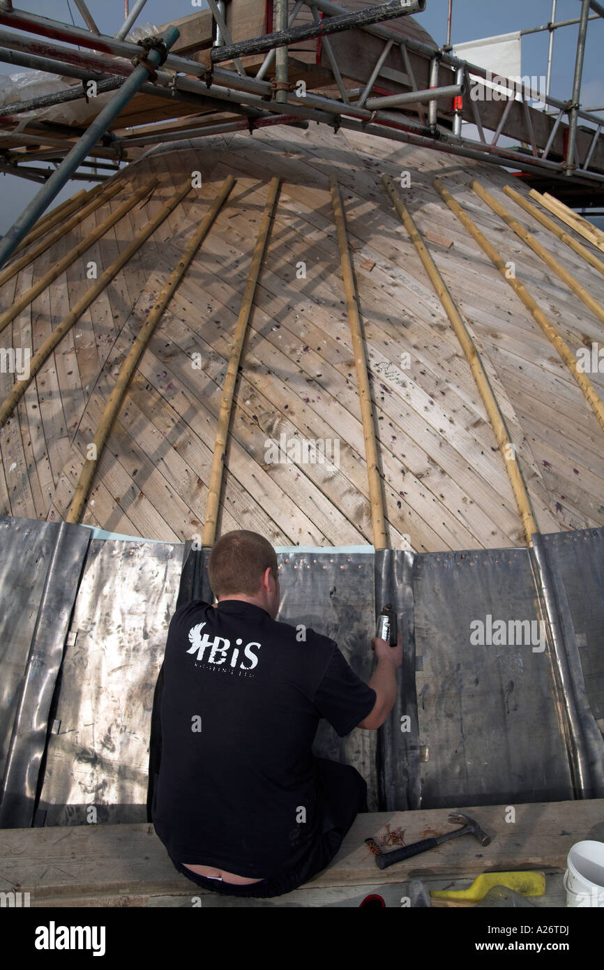 Young skilled man fixes lead sheet to a domed roof Stock Photo