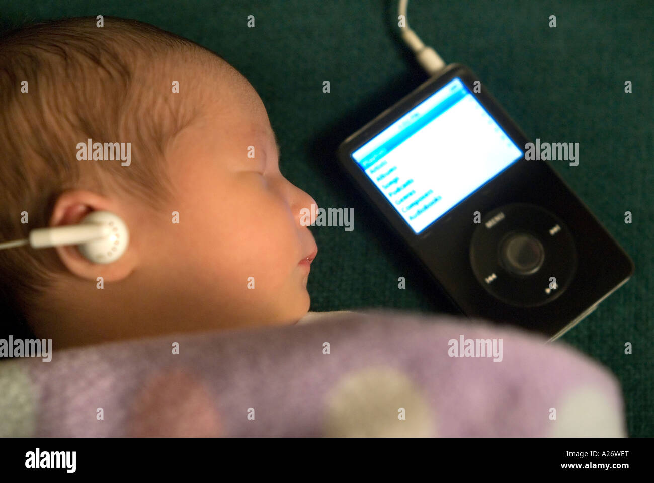 Sleeping newborn baby 7 days old Sleeping Apparently listening to classical music on an mp3 player Stock Photo