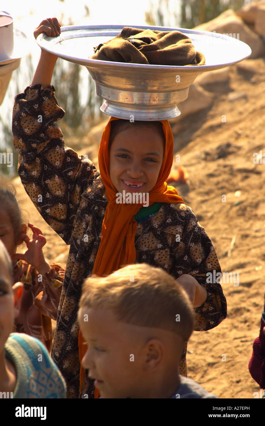 Young Egyptian Girl Carrying Pots And Dishes On Her Head Smiling Stock ...