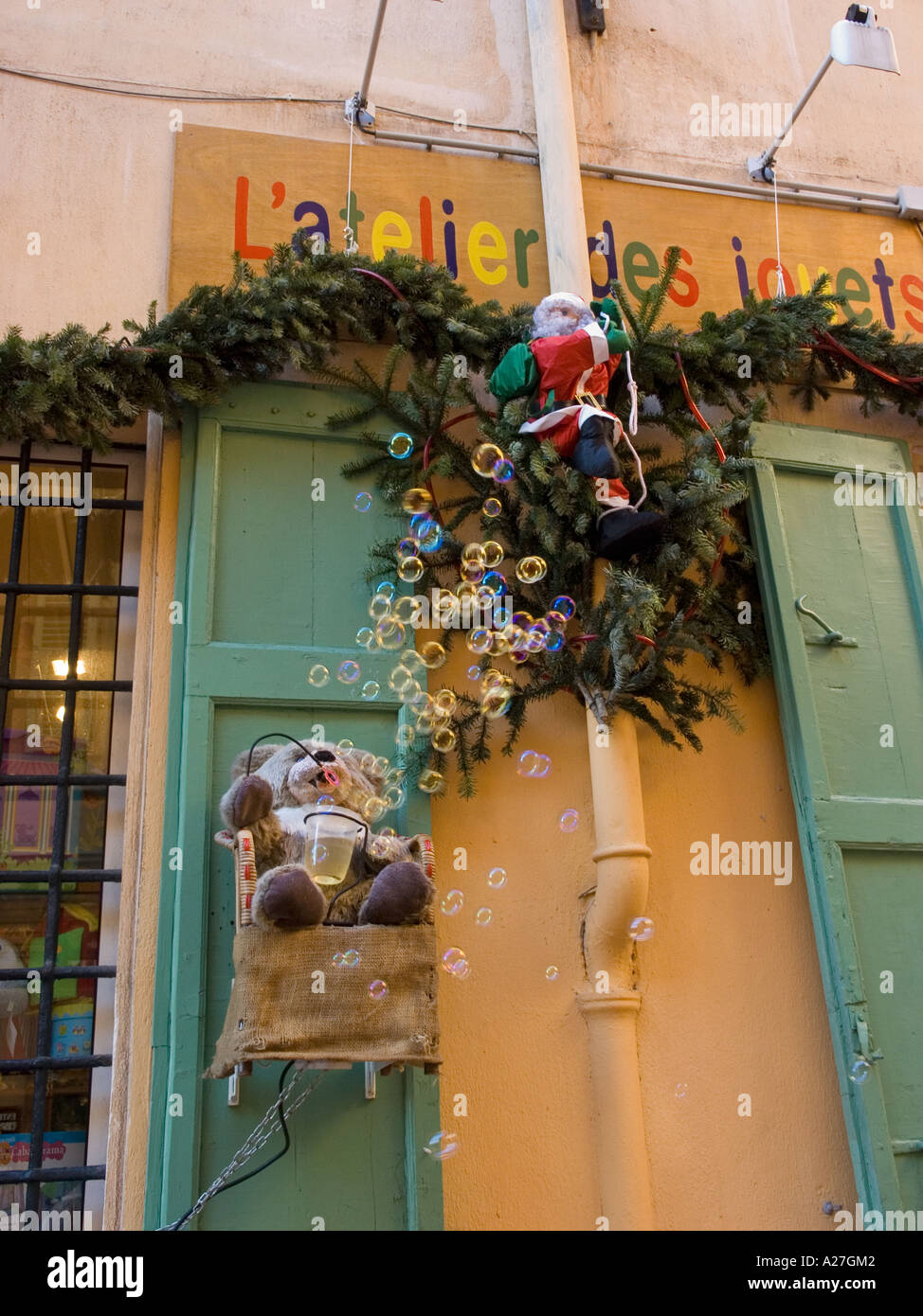 Innovative marketing displayed by a joke and toy shop in Nice, France. Santa climbs a drainpipe while a teddy-bear blows bubbles Stock Photo