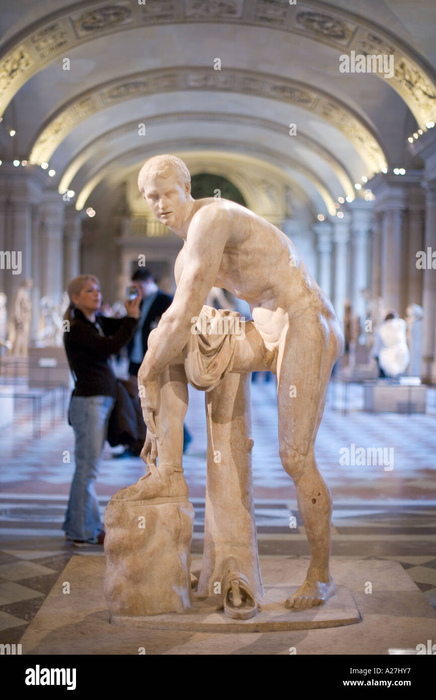 tourist taking pictures in a hall of statues at the louvre in paris