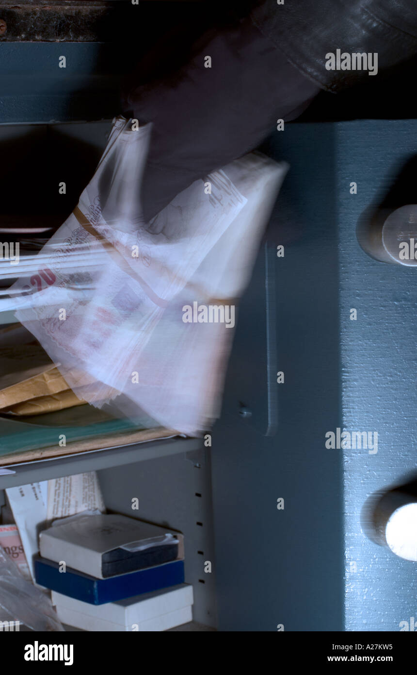 Thief stealing money from a safe Stock Photo