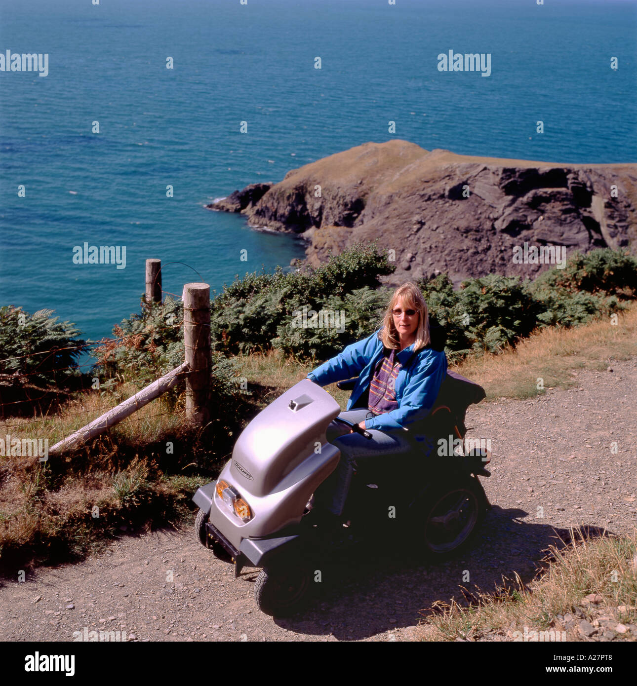 A disabled woman driving an all terrain motorised electric vehicle mobility scooter on the coastal path Llangranog Ceredigion Wales UK   KATHY DEWITT Stock Photo
