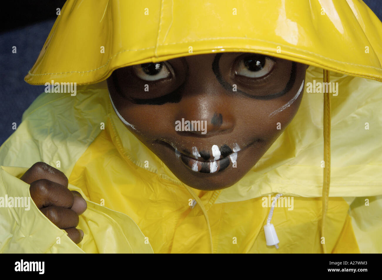 Young black african boy in wet weather clothes and with face paint Stock Photo