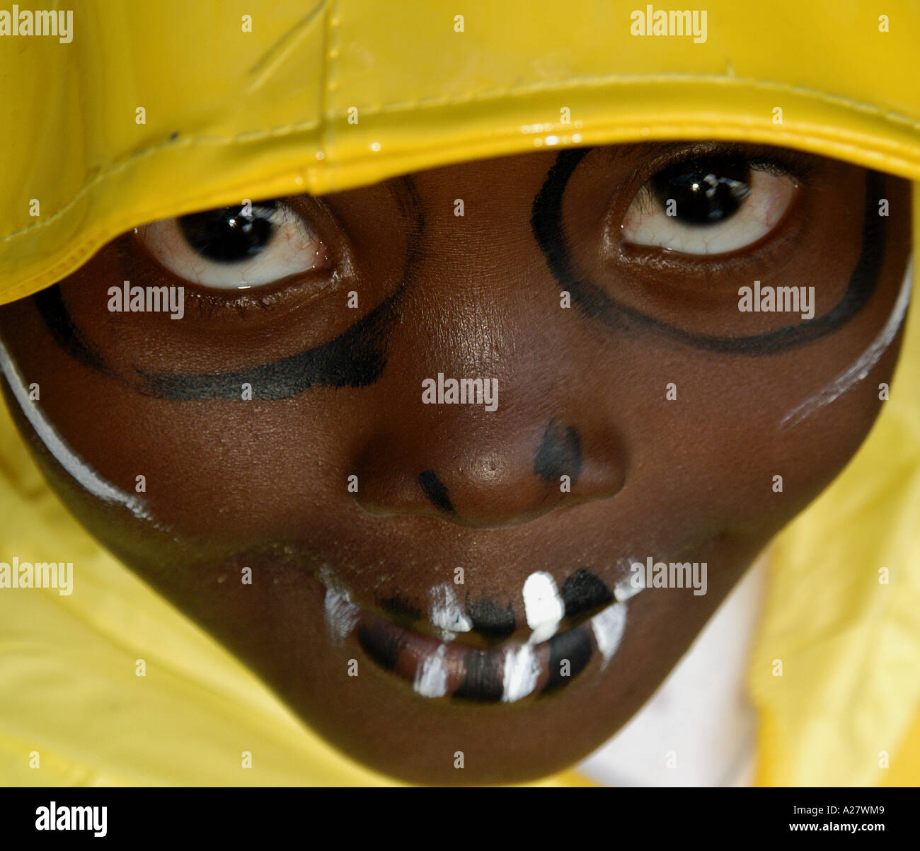 Young black african boy in wet weather clothes and with face paint Stock Photo