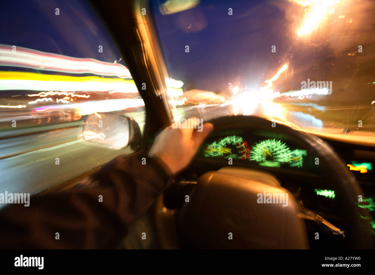 Interior view of person driving at night with lights blurring by.  Shot from drivers perspective. Stock Photo