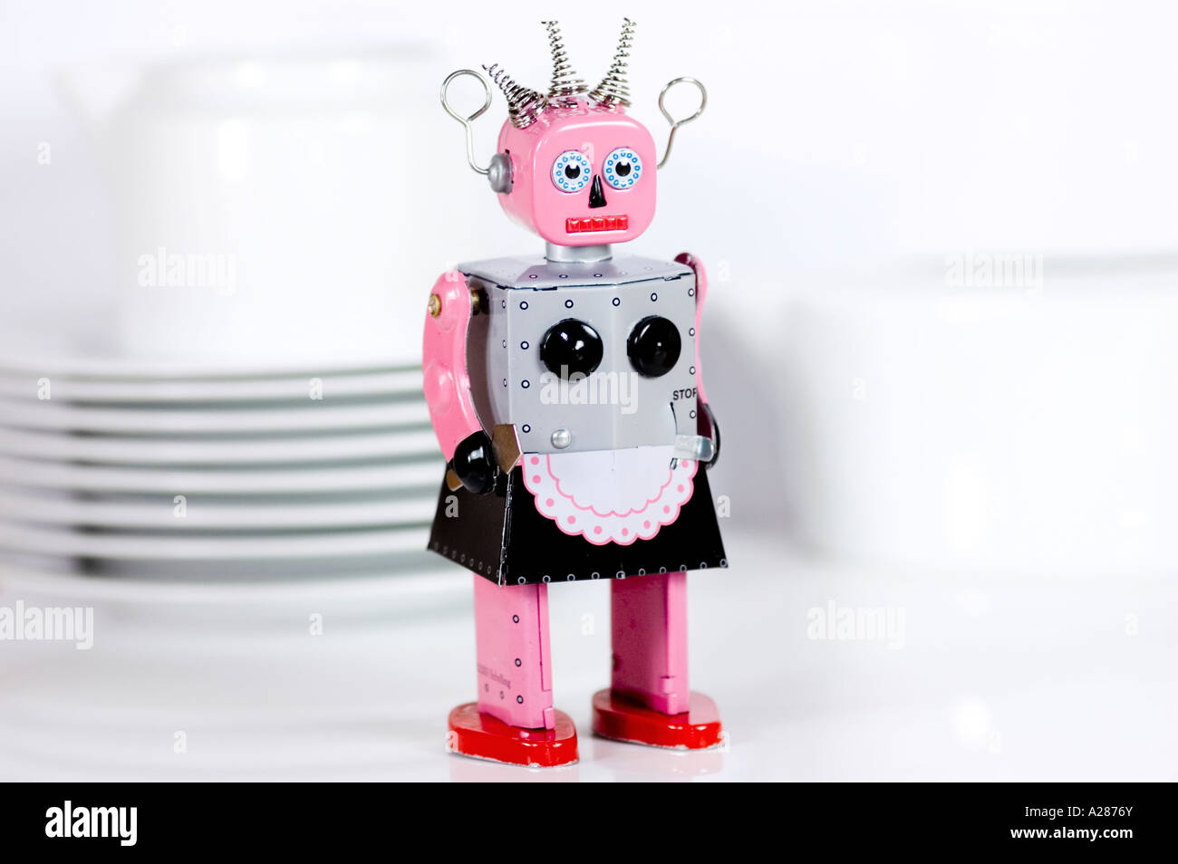 Female tin toy robot standing in front of dishes Stock Photo