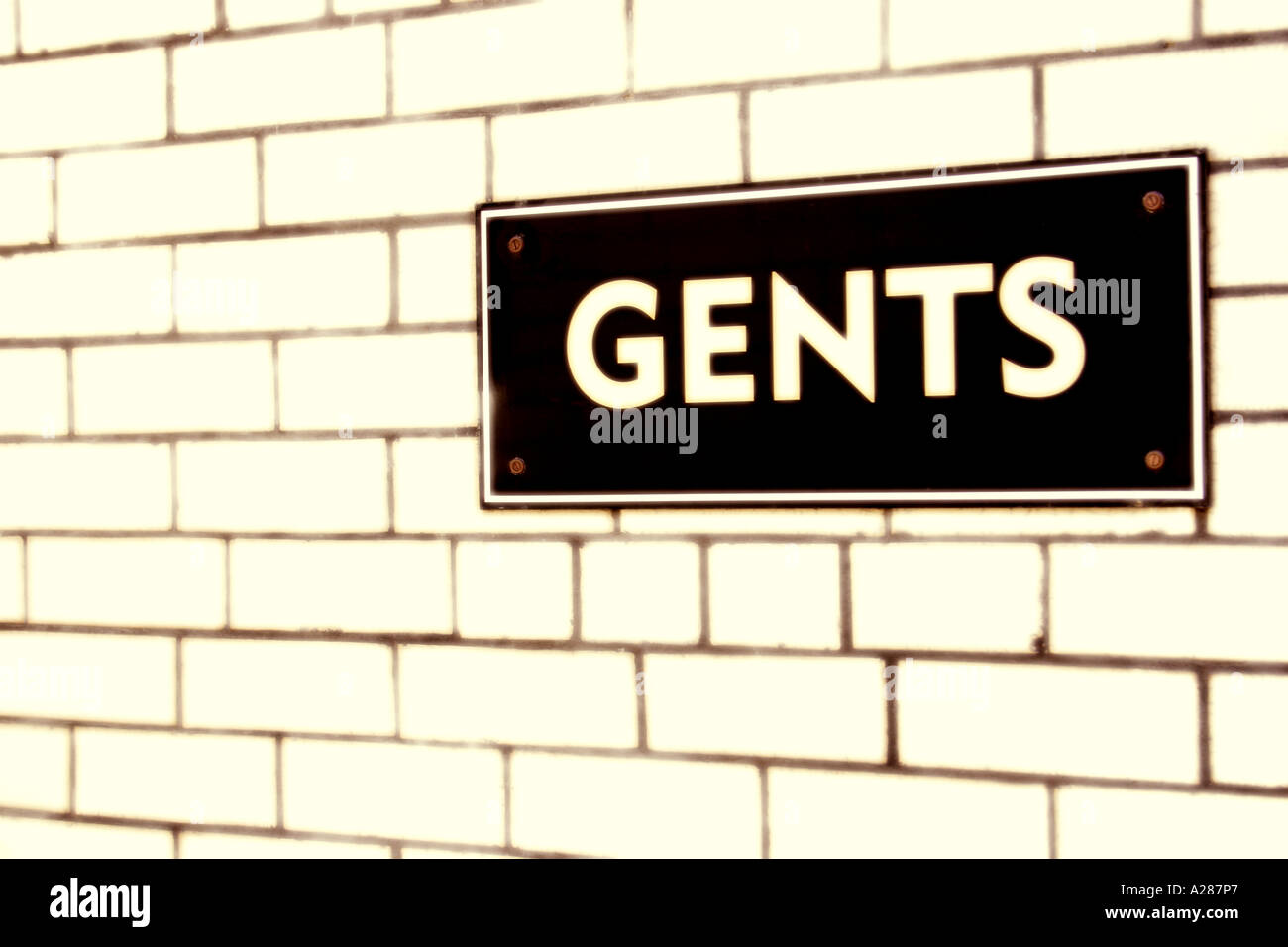 Gents sign on tiled wall of public toilet Digitally manipulated Stock Photo