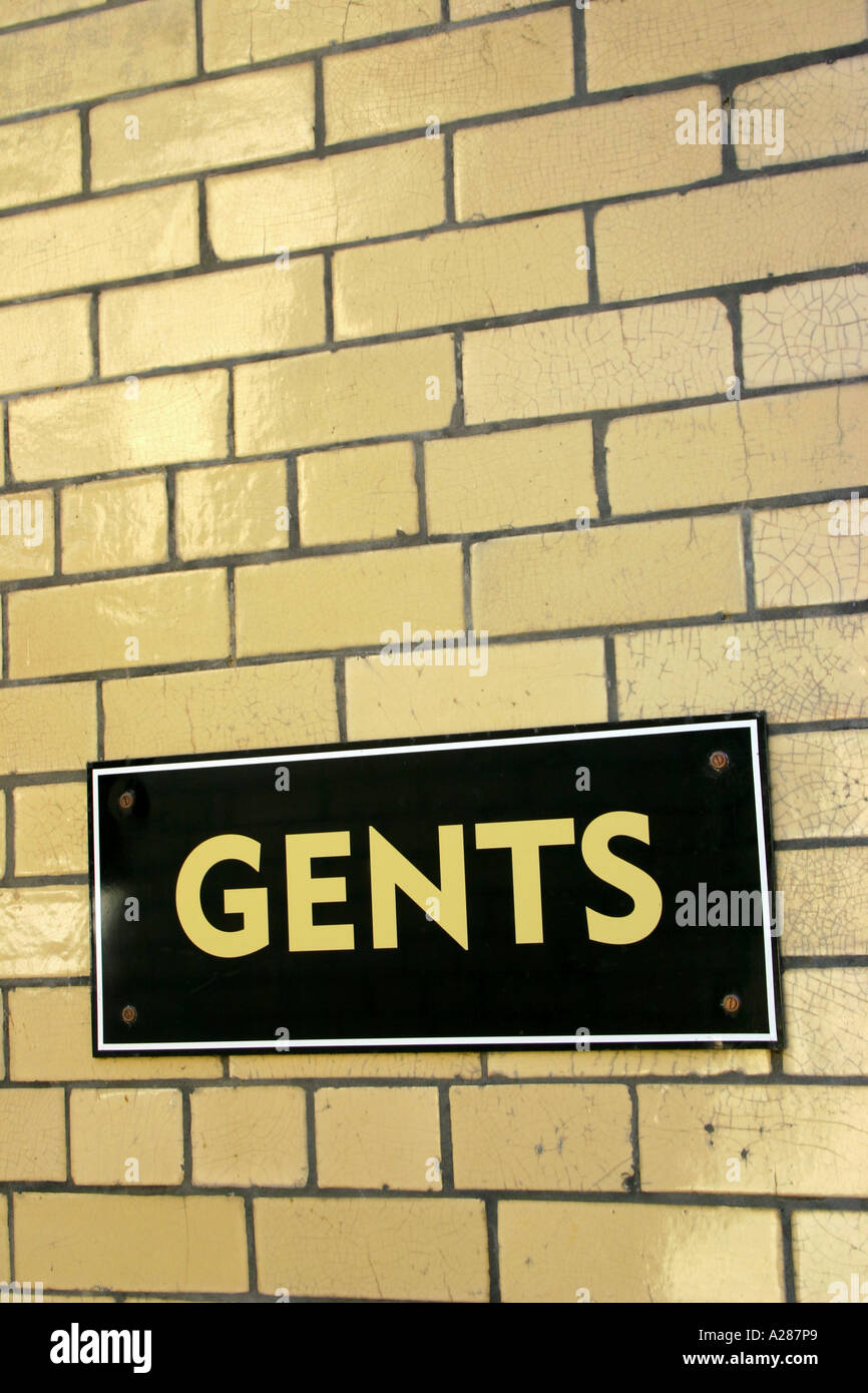 Gents sign on tiled wall of public toilet Stock Photo