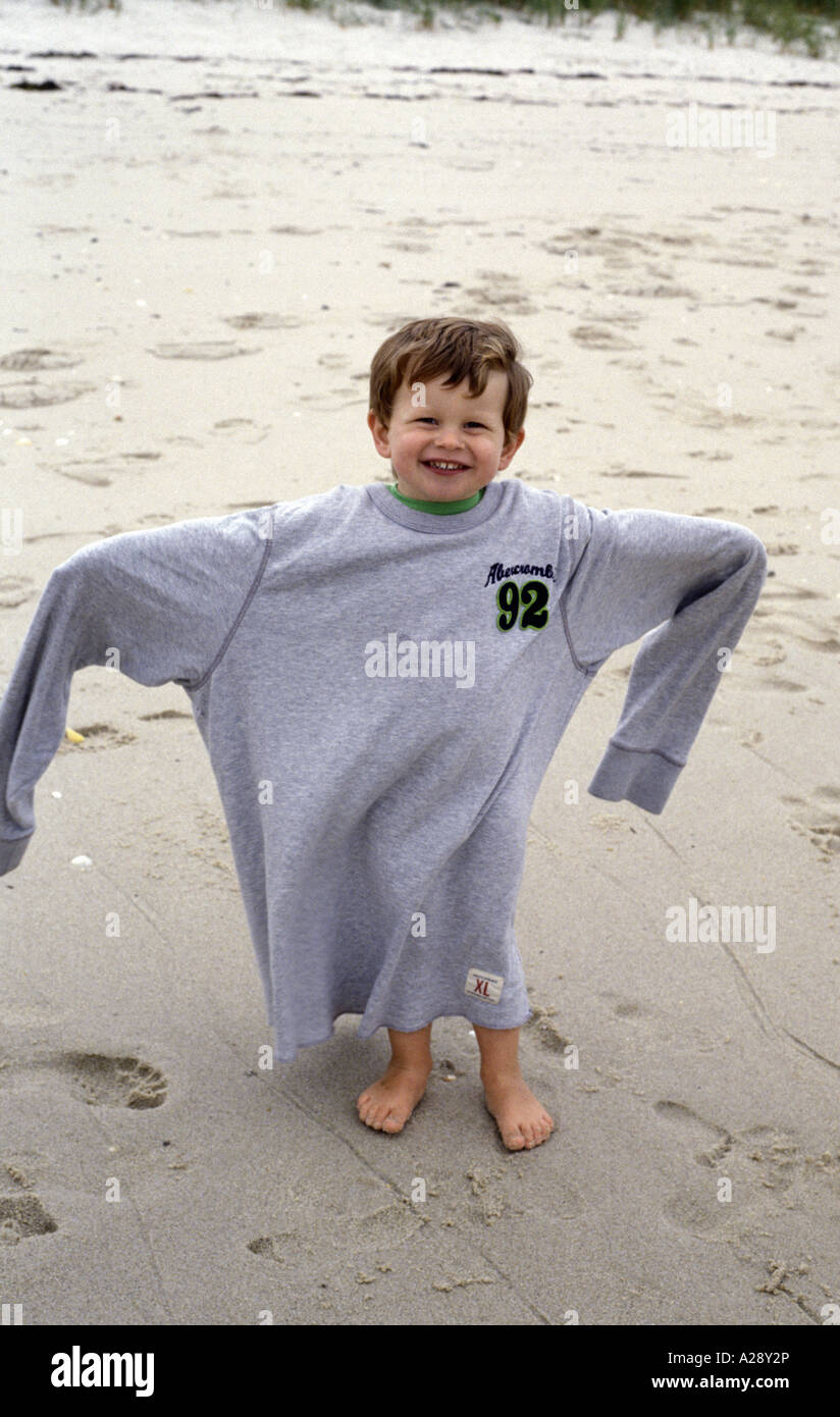 a young boy on a beach in the UK with an adult top on Stock Photo