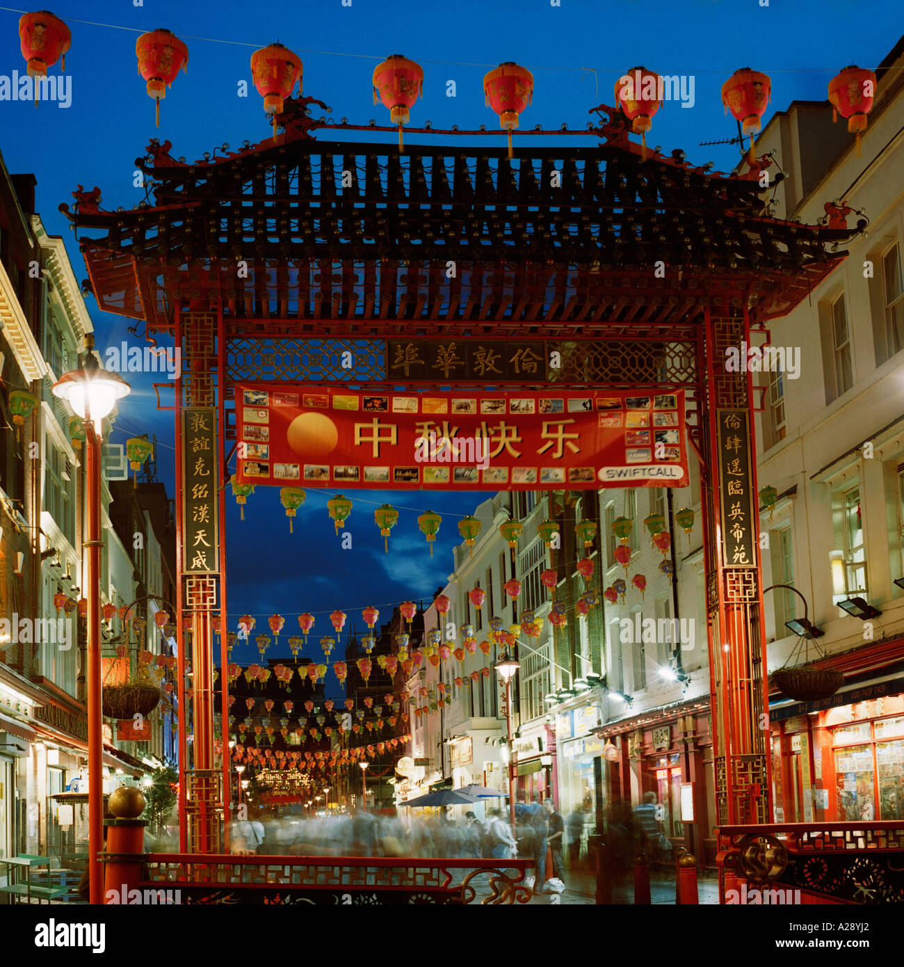 Dusk shot of Chinatown, Gerrard Street, Westminster, London, during Chinese New Year; inc. ceremonial gate, lanterns, flags, shop-fronts Stock Photo