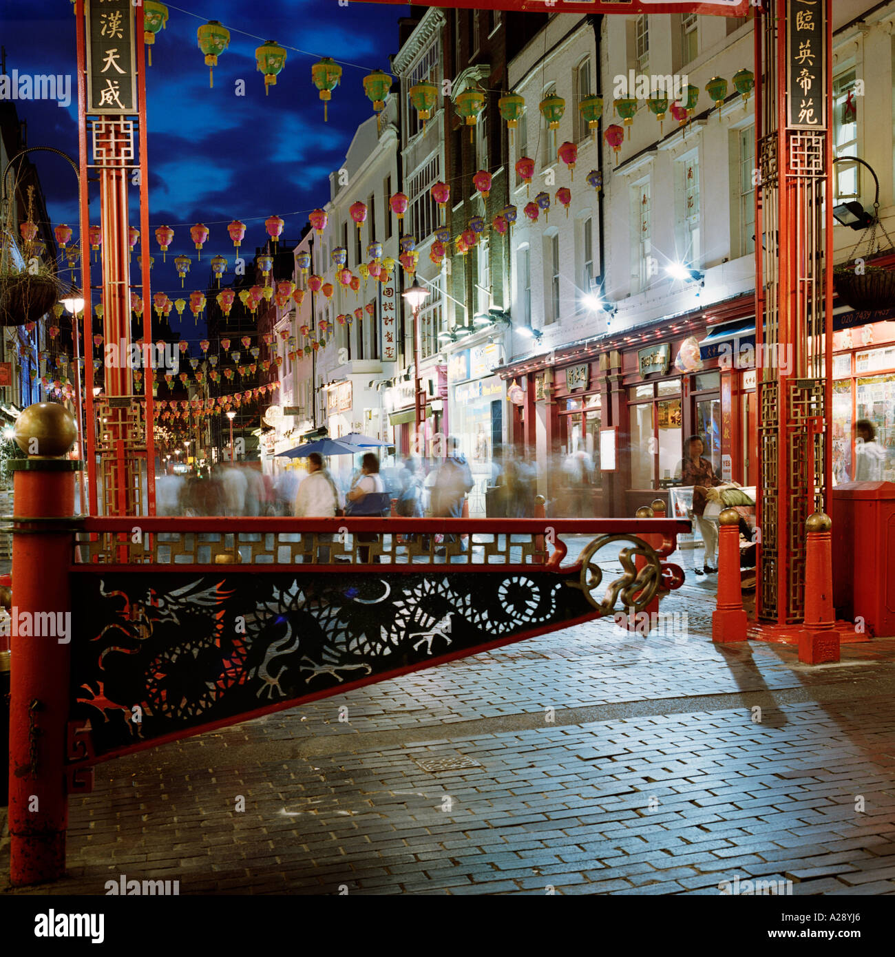 Dusk shot of Chinatown, Gerrard Street, Westminster, London, during Chinese New Year; inc. ceremonial dragon access gate, lanterns, flags, shop-fronts Stock Photo