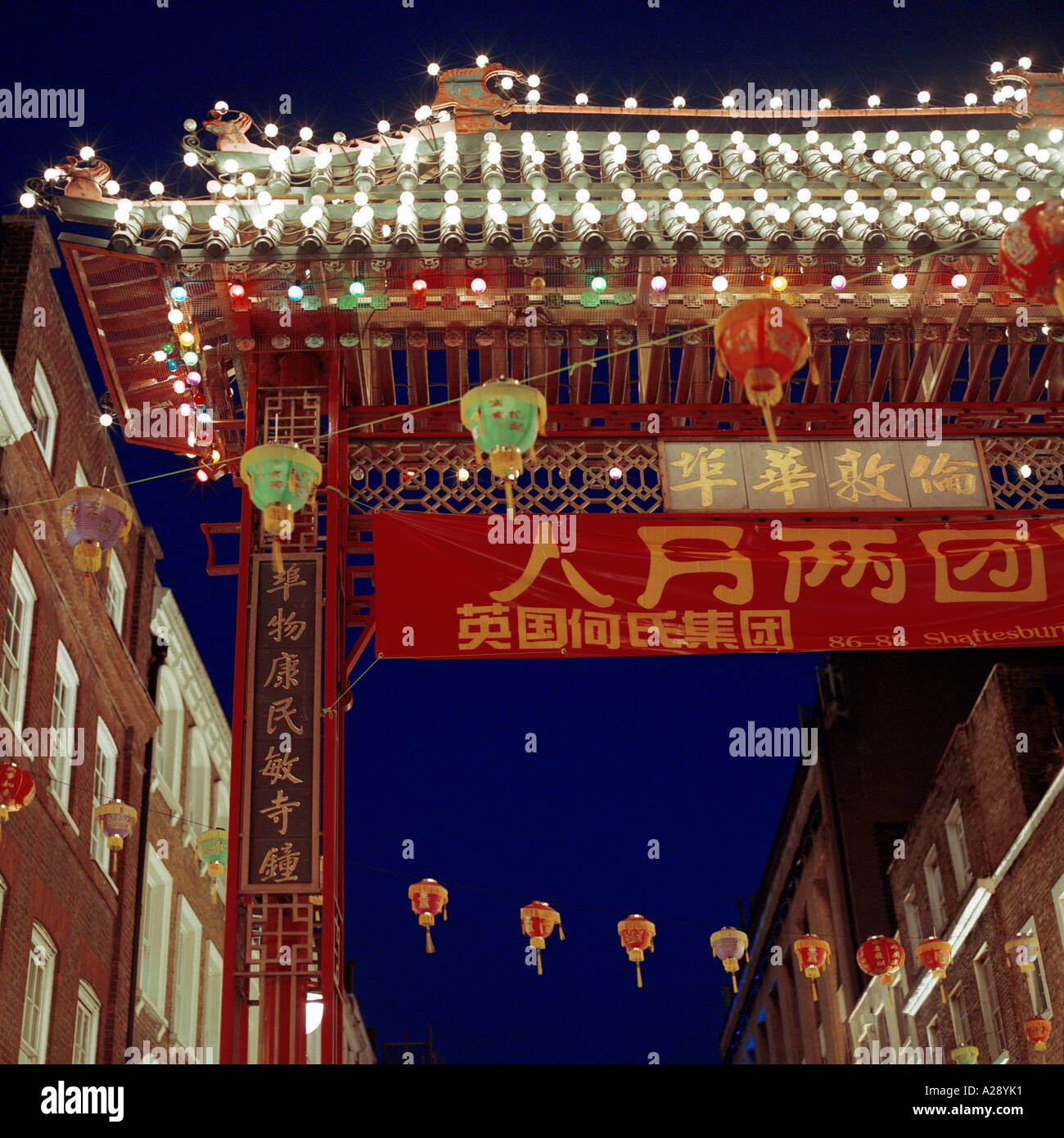 Dusk shot of Chinatown, Gerrard Street, Westminster, London, during Chinese New Year; inc. ceremonial gate, lanterns, flags, shop-fronts Stock Photo
