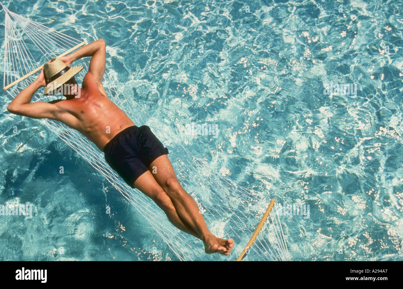 Man relaxing in hammock over water Stock Photo