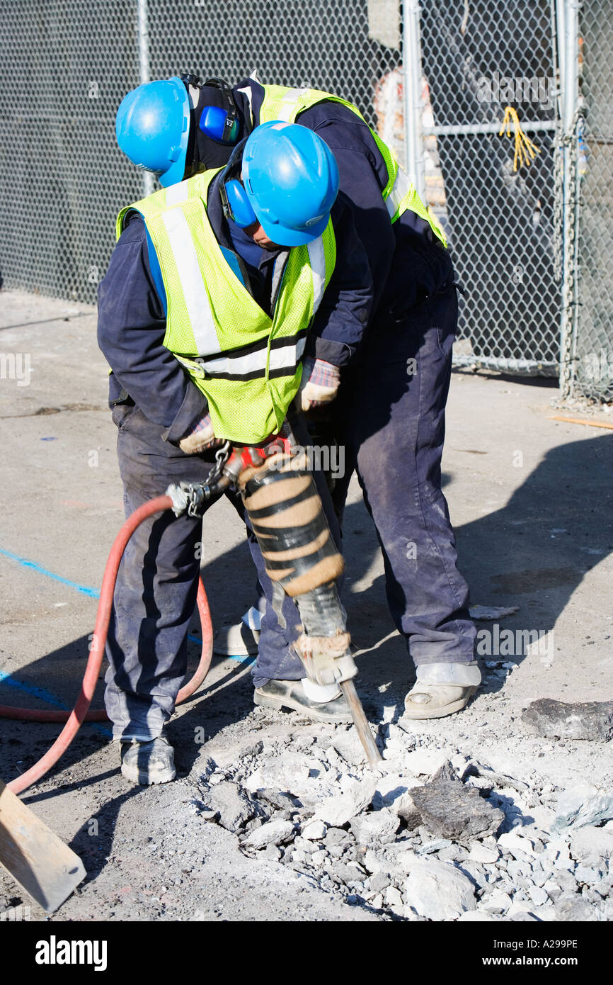 TWO MEN WITH JACKHAMMERS DRILLING A HOLE, NOISE, NOISY Stock Photo