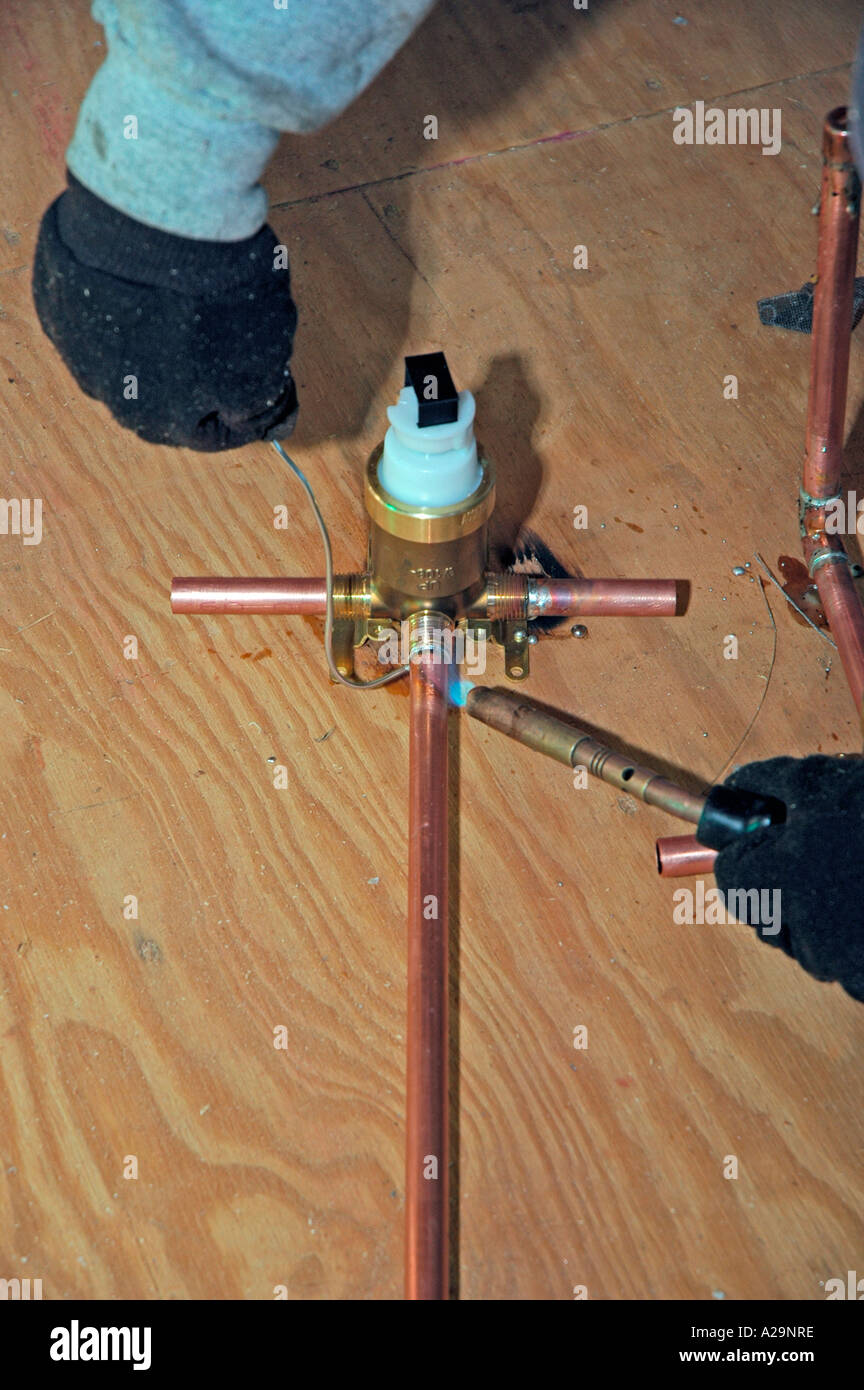 Plumbing installation crew putting in plastic and copper pipes into new home construction in USA