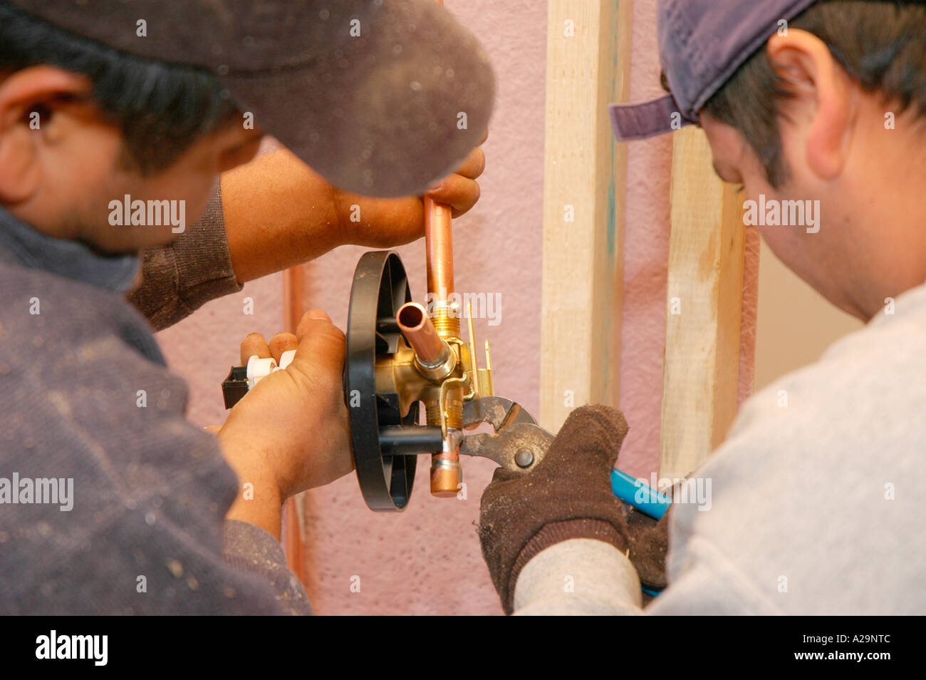 Plumbing installation crew putting in plastic and copper pipes into new home construction in USA