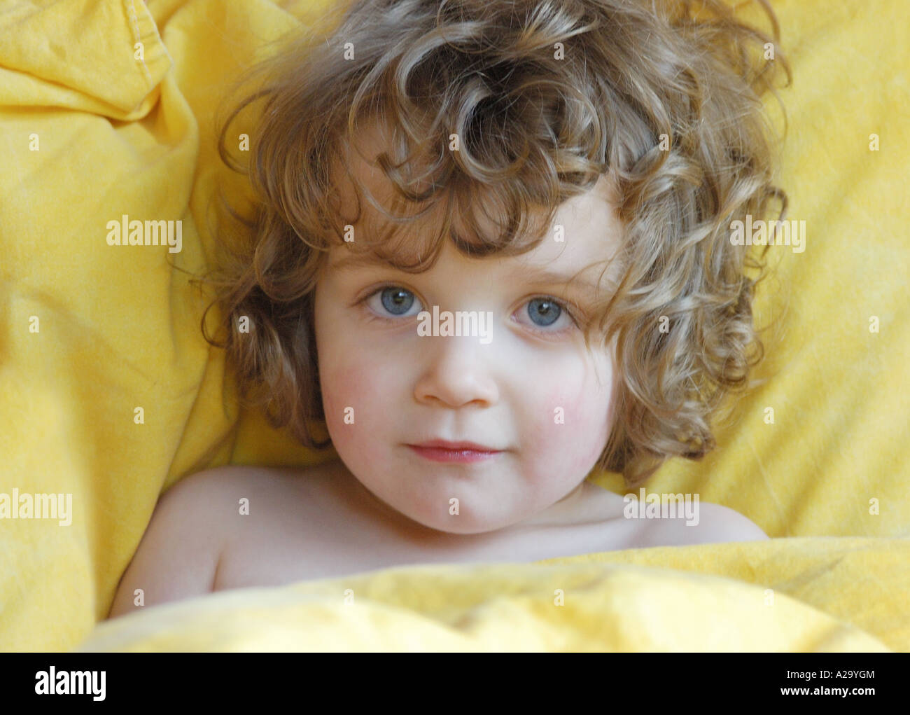 Girl with curley hair laying in bed in the morning Stock Photo