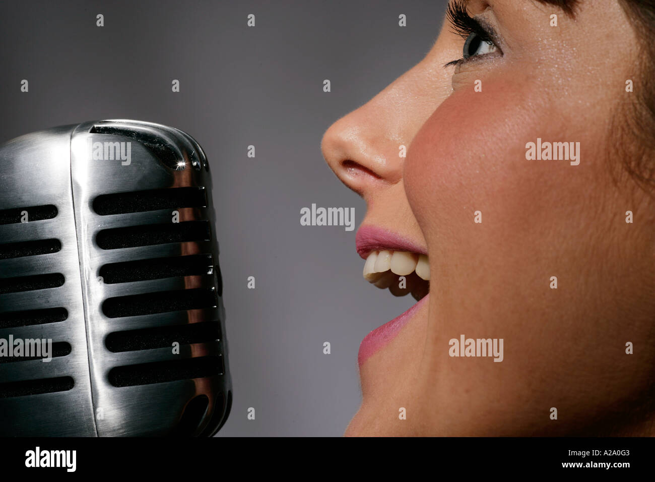 Singing into a fifties or sixties style microphone night nightime nightclub club bar Stock Photo