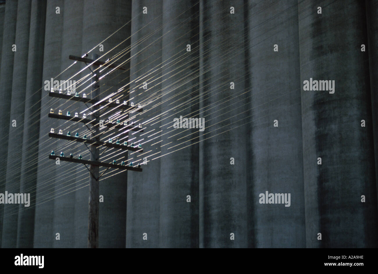 Telephone lines backlit in front of a concrete grain elevator in Topeka