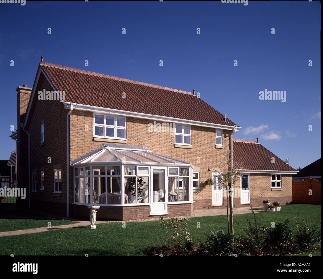 Rear elevation of  new detached brick house with pitched roof and conservatory. Stock Photo