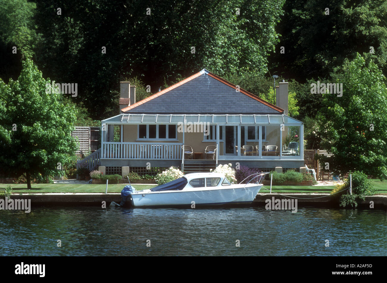 A small motor cruiser moored by a riverside house on the River Thames near Henley on Thames Oxfordshire England UK Stock Photo