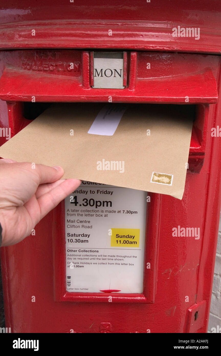 Sending a letter, posting a letter into a red uk postbox Stock Photo