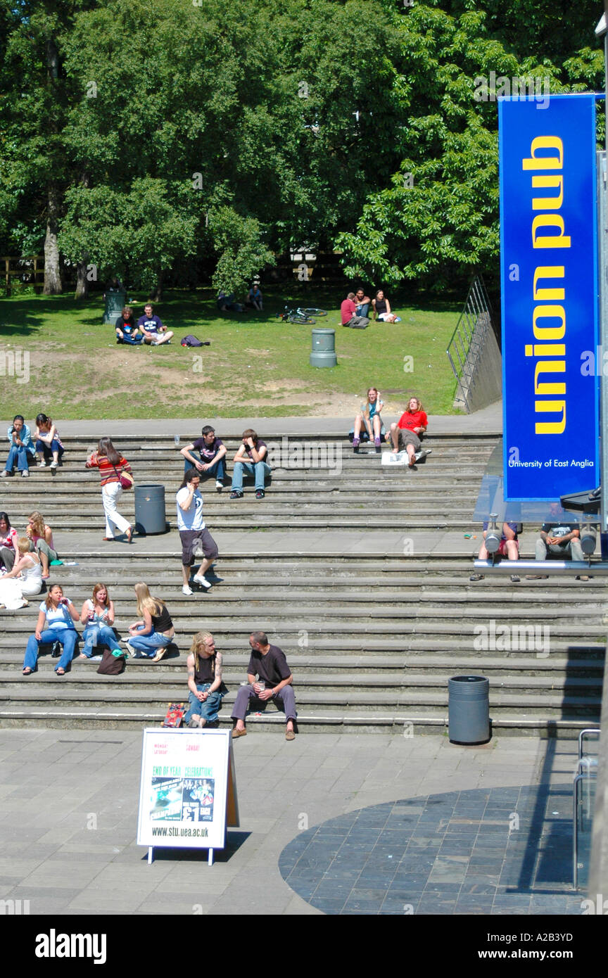 Students relaxing on steps in the sunshine on campus at the University of East Anglia, UEA, Norwich, UK Stock Photo