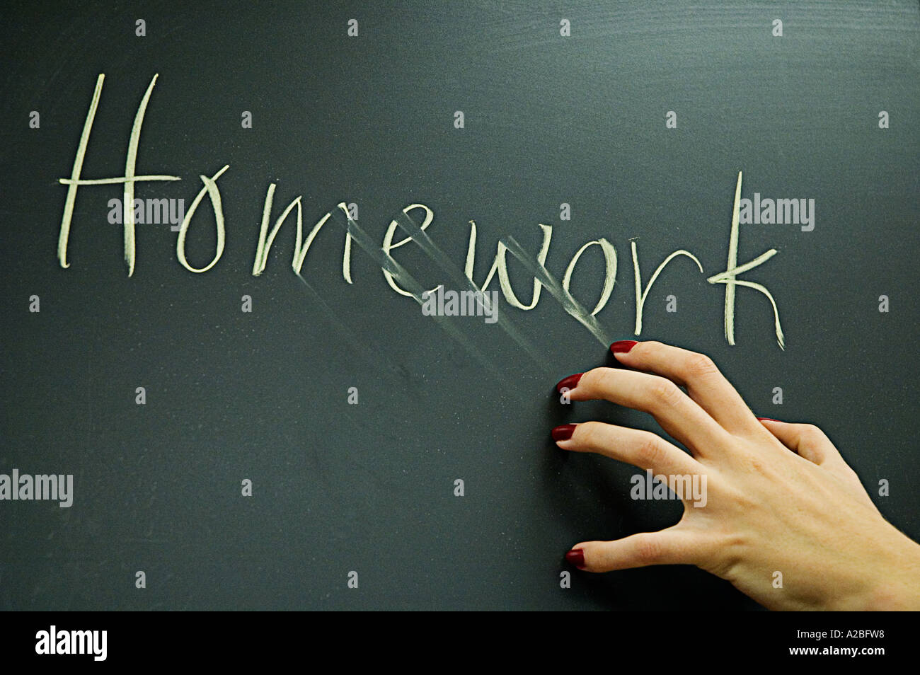 nails against blackboard which says homework Stock Photo
