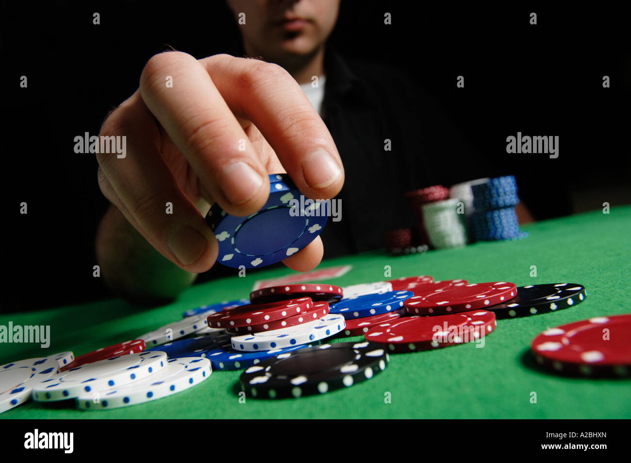 Young man putting chips into pot in poker game Stock Photo - Alamy