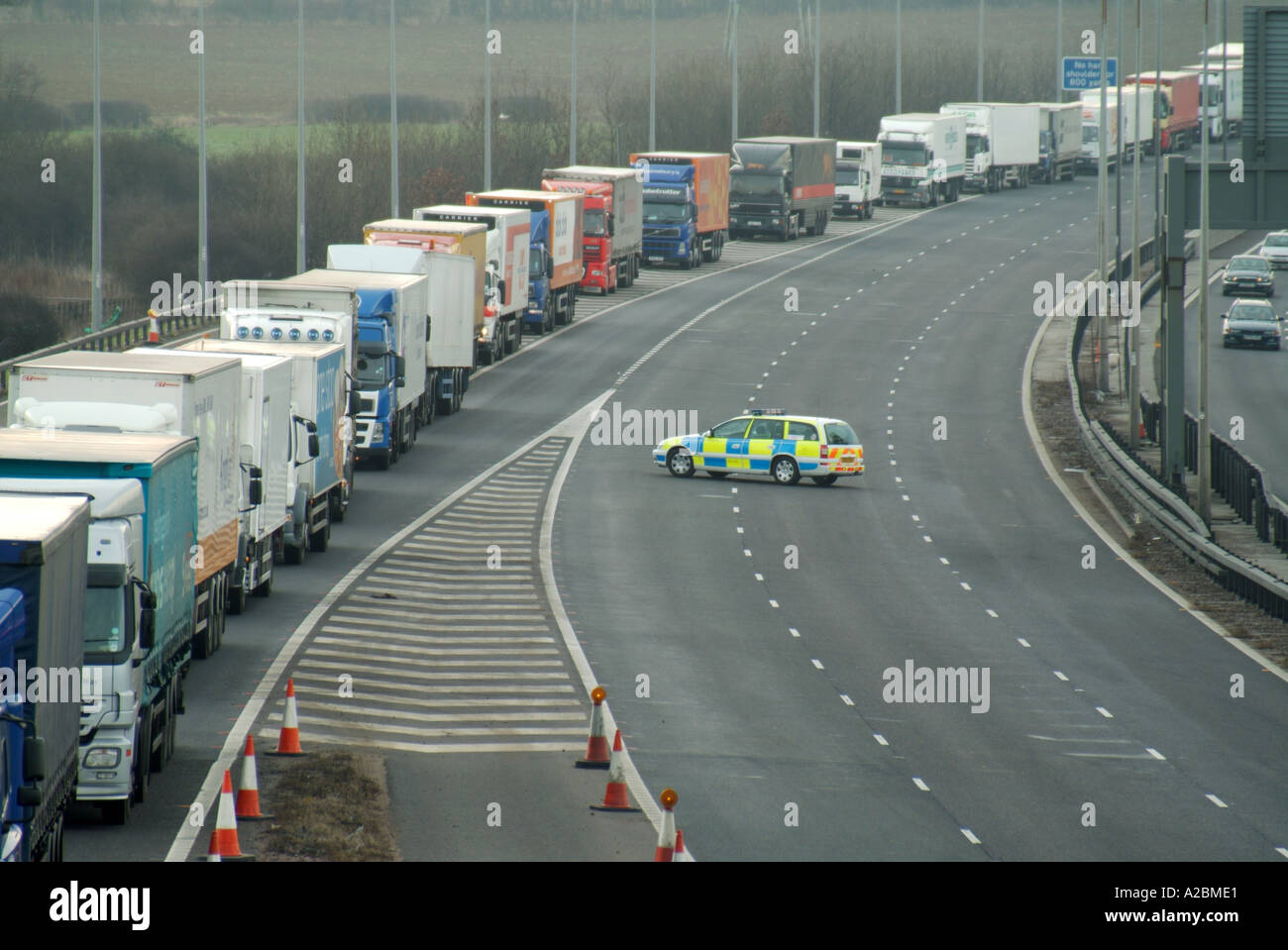 M25 motorway closed due to serious accident requiring long tailback queue of lorries to turn-around & exit in wrong direction supervised by police UK Stock Photo