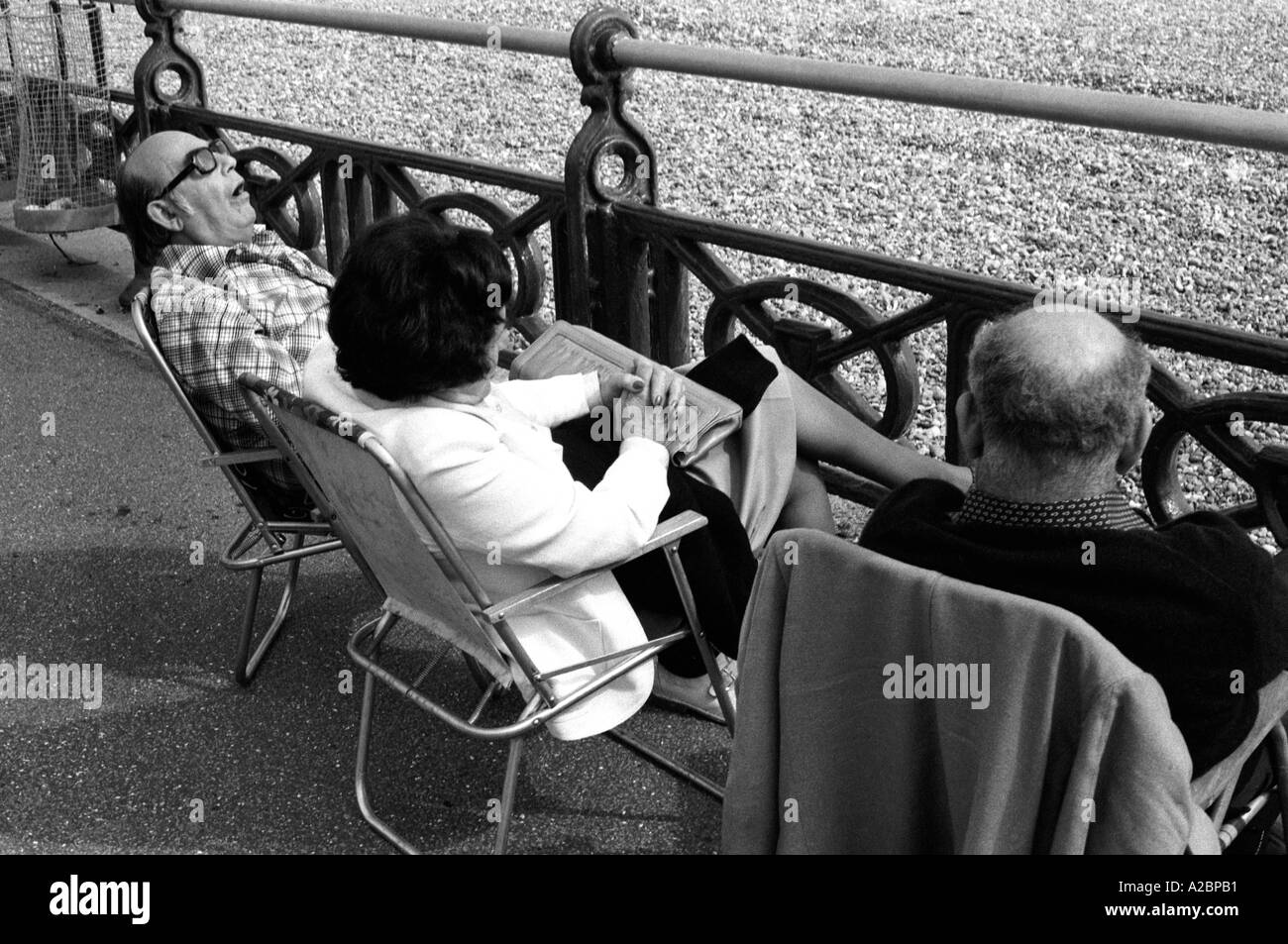 Two men and woman one sleeping seafront Brighton England 1979 35mm b/w Stock Photo