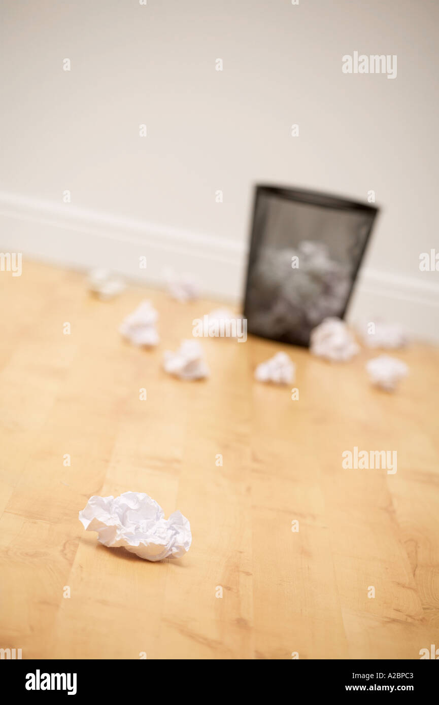 LITTER BIN AND CRUMPLED WASTE PAPER ON WOOD OFFICE FLOOR Stock Photo