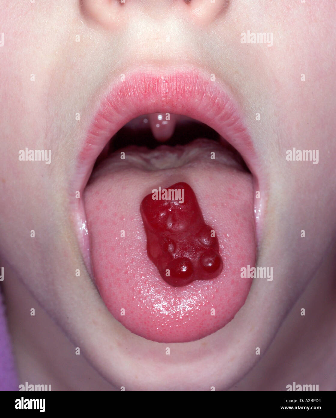 child with a gummy bear vitamin on her tongue Stock Photo