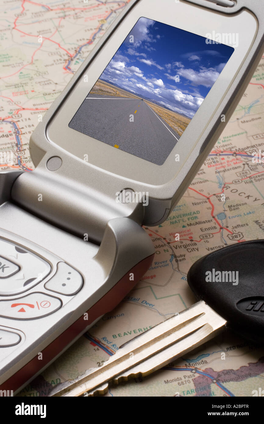Car keys and a cellular telephone with an image of an open road on top of a road map Stock Photo