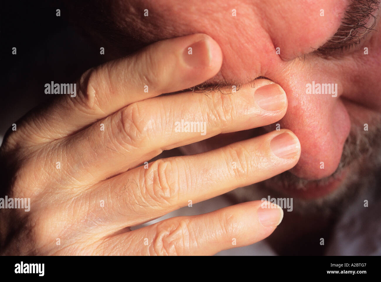 Elderly man under quarantine at home alone during shutdown frowning with hand to brow, frightened at the thought of coronavirus covid virus infection. Stock Photo