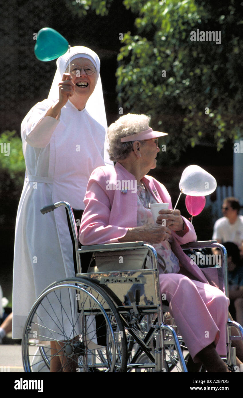Nun holding a balloon pushing an elderly woman in a wheelchair in a