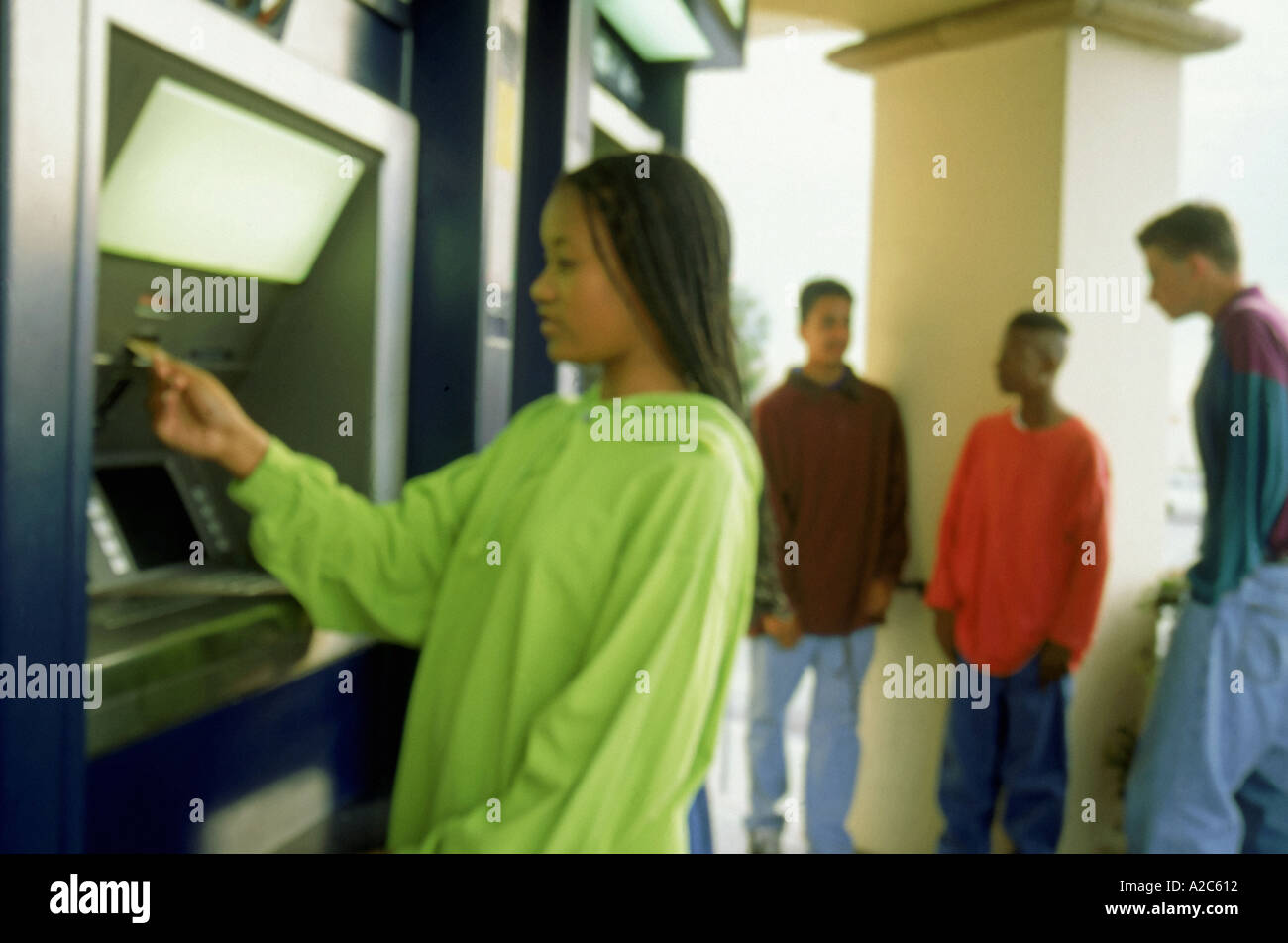 Young African American girl using automatic teller at bank teens hanging out POV ethnic ethnicity multi diverse diversity multicultural Stock Photo