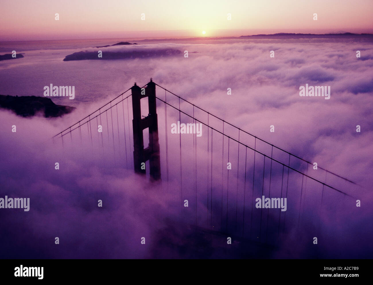 Aerial view of Golden Gate Bridge in San Francisco CA with fog obstructing the visibility as the sun rises in the distance Stock Photo