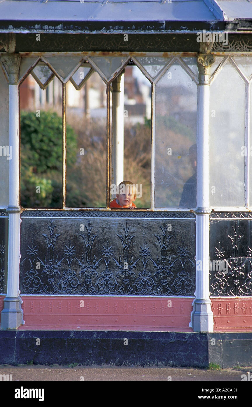 Small boy looking out through broken pane of Victorian Shelter on the