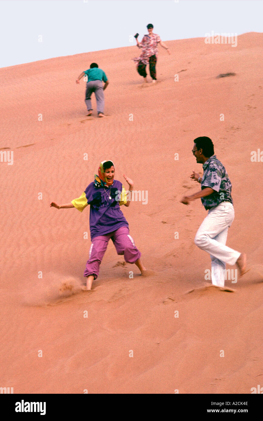 Oman. Wahiba Sands. Tourists visting the Wahiba Sands in the interior. Climbing and sliding down sand dunes is great fun Stock Photo