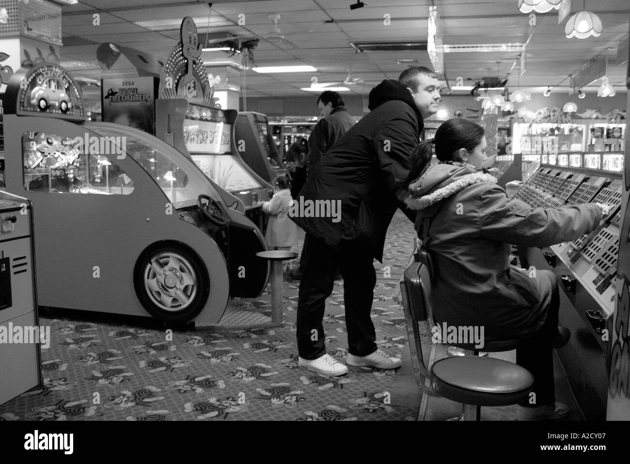 black and white image off an arcade with people playing the machines Stock Photo