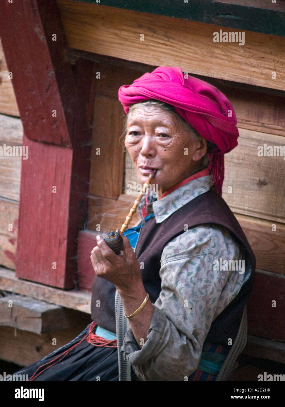 ethnic Nu woman sitting and smoking her corncob pipe Nujiang Valley Yunnan China Stock Photo